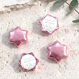 Pink foil-covered chocolate stars with a round printed label and floral accents