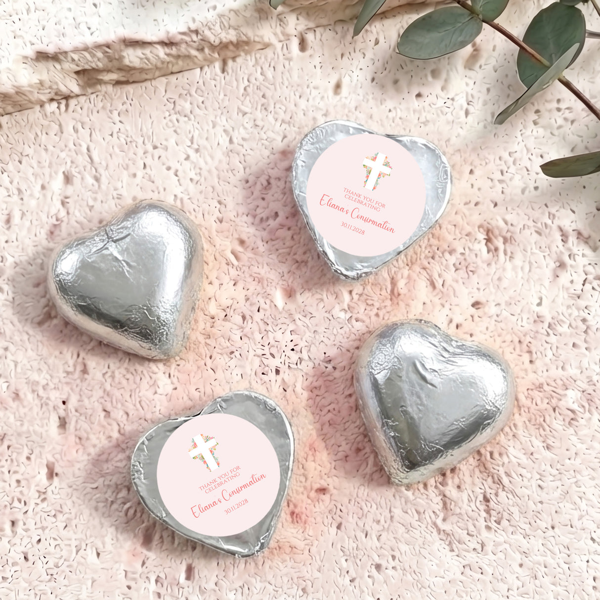 Silver foil heart chocolates with white round label and small cross emblem