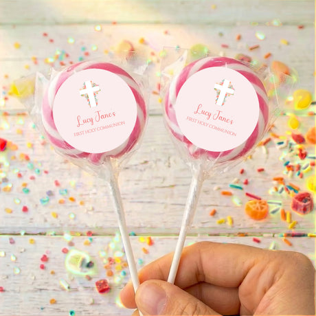 Two First Holy Communion lollipops with pink round labels, white cross and custom name