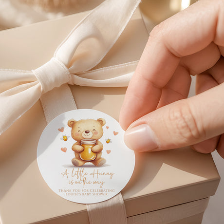 Round baby shower favor label with teddy bear holding honey jar illustration