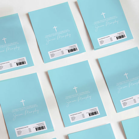 Light blue printed chocolate wrappers with cross, handwritten-style prayer text, and barcode.