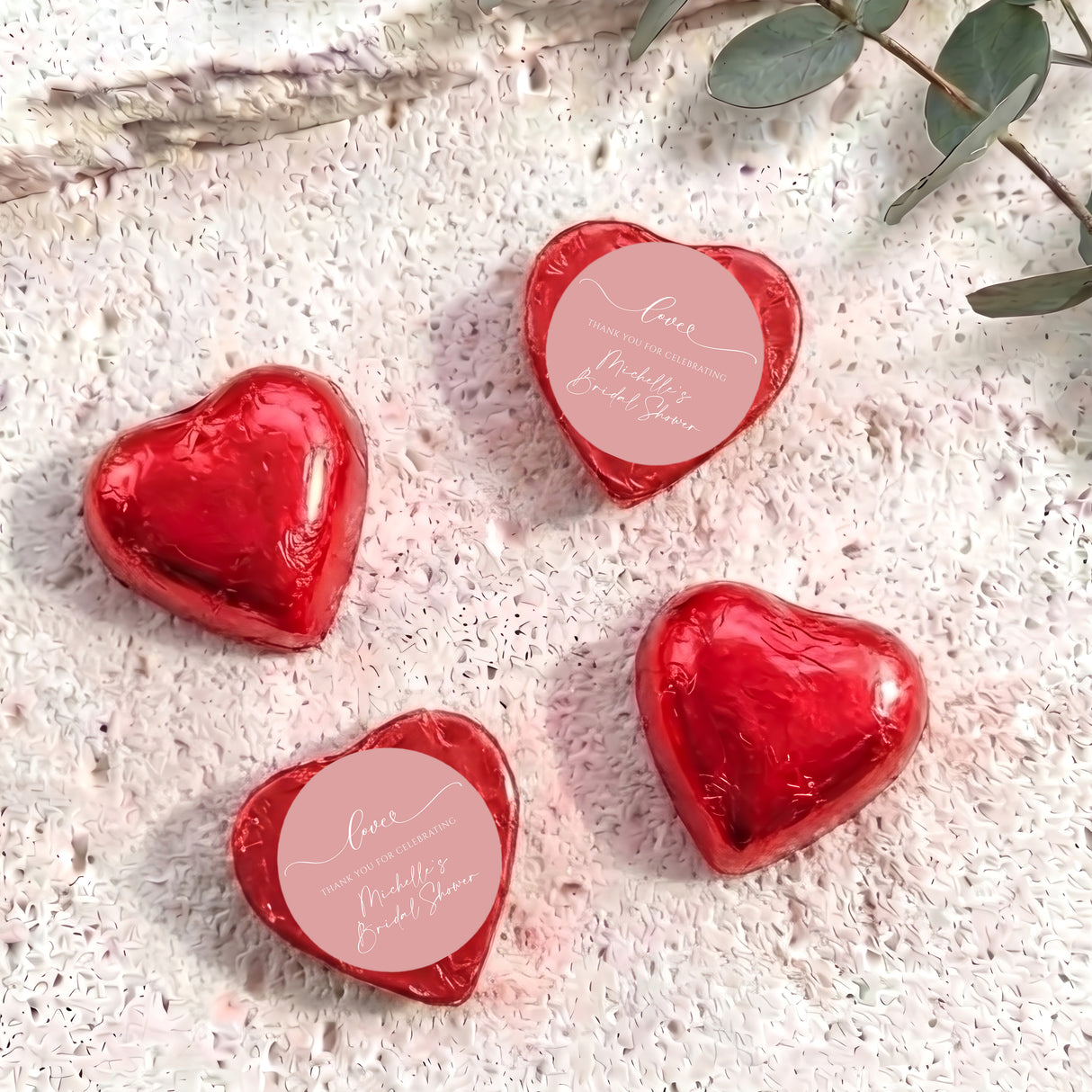 Red heart-shaped foil-covered chocolates with a round pink label on top