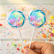 Personalised tie-dye lollipop pair with colorful circular labels on clear sticks