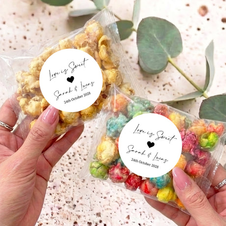 Personalised popcorn bags with clear wrap, round label with hearts and names; held in hands