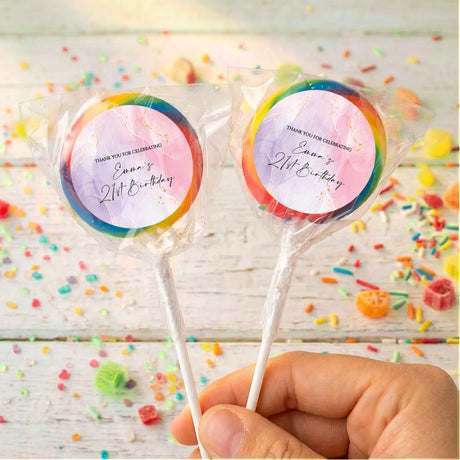 Personalised birthday lollipops with dark purple and orange swirled wrappers, held by hand