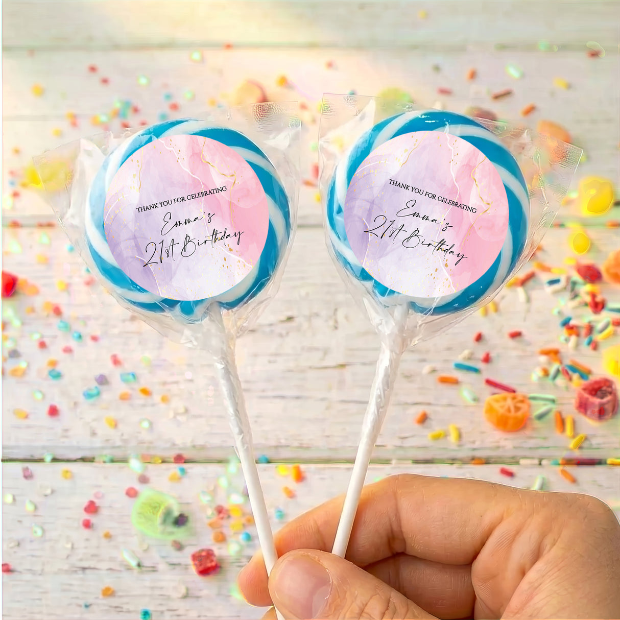 Personalised birthday lollipops with blue swirled wrappers, held by hand