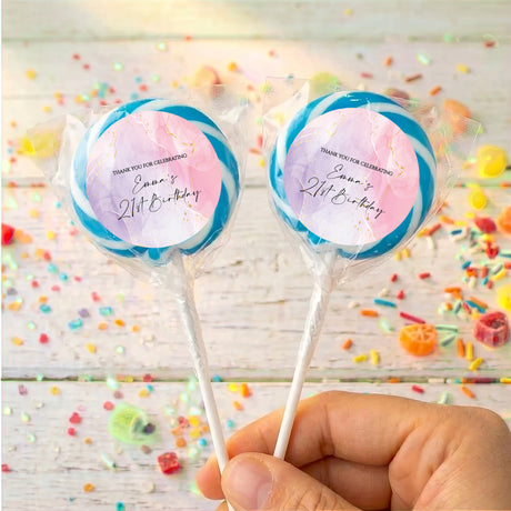 Personalised birthday lollipops with blue swirled wrappers, held by hand
