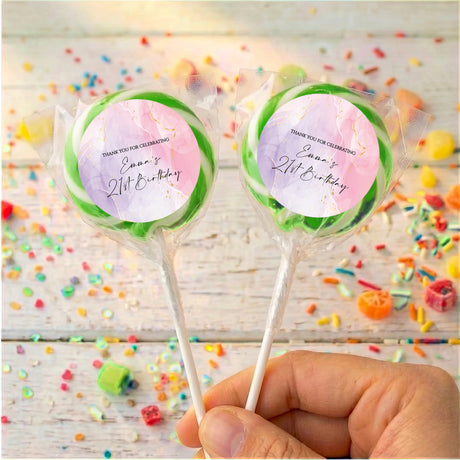 Personalised birthday lollipops with green swirled wrappers, held by hand