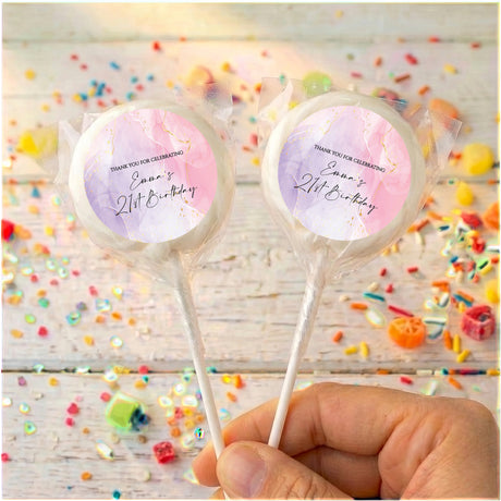 Personalised birthday lollipops with pink swirled wrappers, held by hand