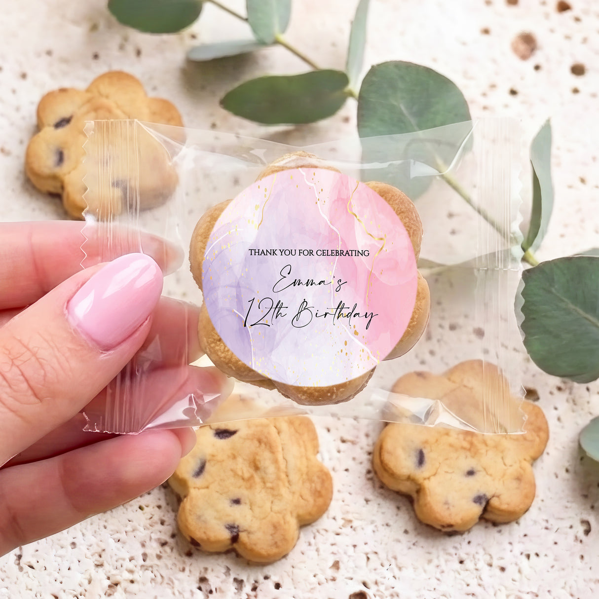 Personalised kids birthday cookie with round pink/purple label, chocolate chips; held in hand