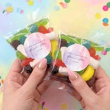 Two clear lolly bags with colorful sweets and matching pink marble thank-you labels