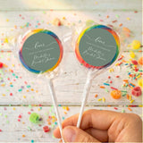 Personalised wrapped lollipops with round sage-green labels and multicolor ribbon edges on sticks