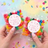Personalised jelly bean bags held by hands, two pink floral round labels, colorful candies