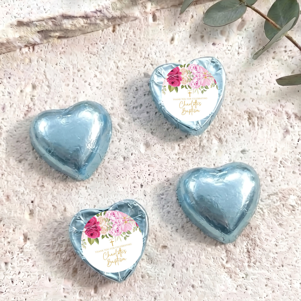 Heart-shaped foil-covered chocolate hearts in light blue, with floral center labels