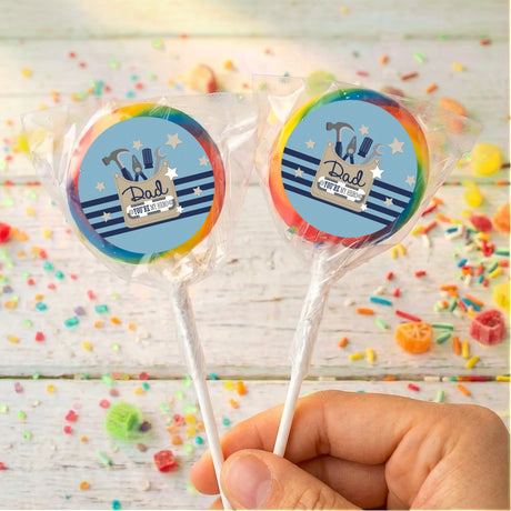 Personalised Father’s Day lollipops with blue “Dad” tools logo, clear wrap, held by hand