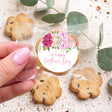 Decorated round cookie with pink and white flowers, 'Happy Mother's Day' text, held in hand