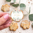 Personalized cookie with floral round label, hand holding; chocolate chip cookies on tray