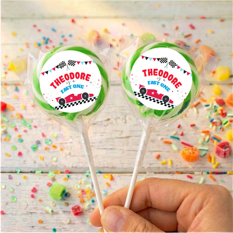 Personalised race car lollipops with “THEODORE” labels, green ribbons, two on sticks