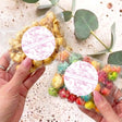 Pink safari-themed popcorn bag set with round white personalised labels, held by hands