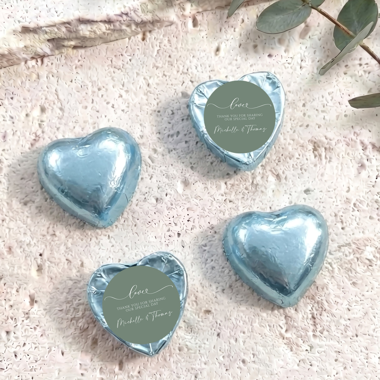 Light blue foil-covered heart chocolates with round personalized thank-you labels