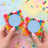 Two personalised jelly bean bags in clear wrappers, light-blue Love stickers, held by hands