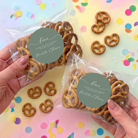 Personalized sage green wedding pretzel gift bags with pretzels and circular name labels