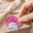 Round unicorn 6th birthday label, "Zara's 6th Birthday" on purple with rainbow