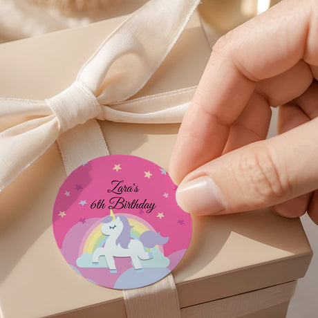 Round unicorn 6th birthday label, "Zara's 6th Birthday" on purple with rainbow