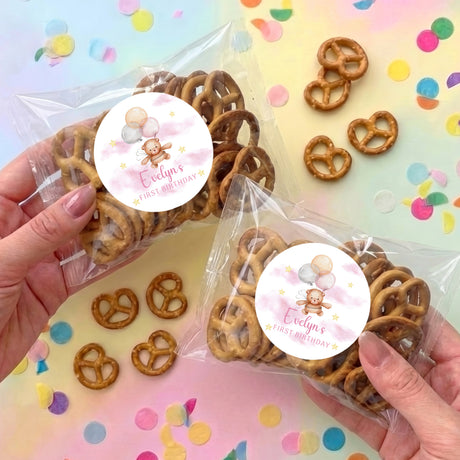 Personalised first birthday pretzel bags with clear wrap, pretzels, and pink teddy balloon stickers