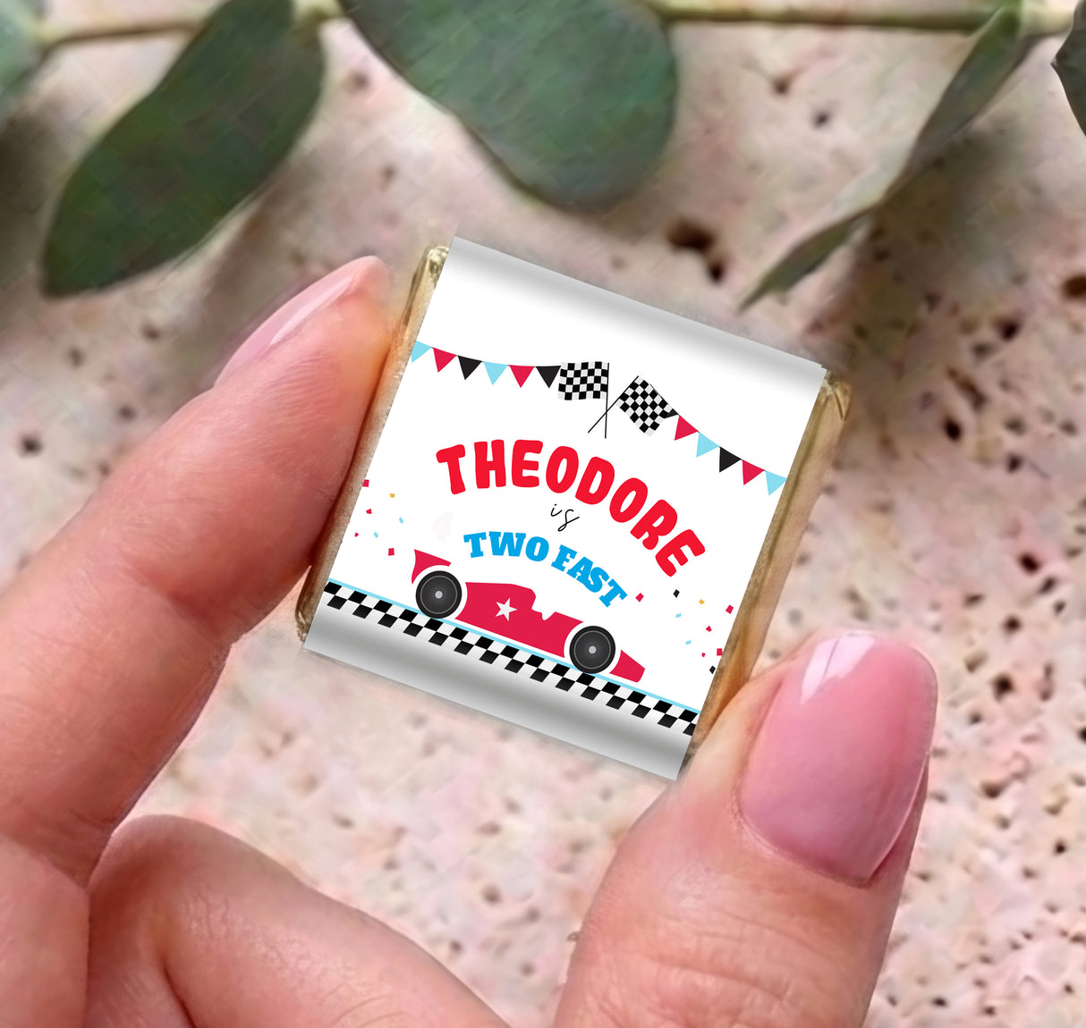 Racing mini chocolate wrapper held in hand: THE ODORE, Two Fast, checkered car design