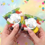 Two personalised baby shower lolly bags held in hands, round stickers with safari animals
