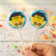 Personalised birthday lollipops with yellow truck labels in blue border, held in hand