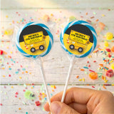 Personalised birthday lollipops with yellow truck labels in blue border, held in hand