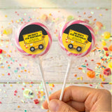 Personalised birthday lollipops with yellow truck labels in pink border, held in hand