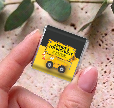 Personalised mini chocolate bar in foil with yellow truck birthday wrapper, held between fingers