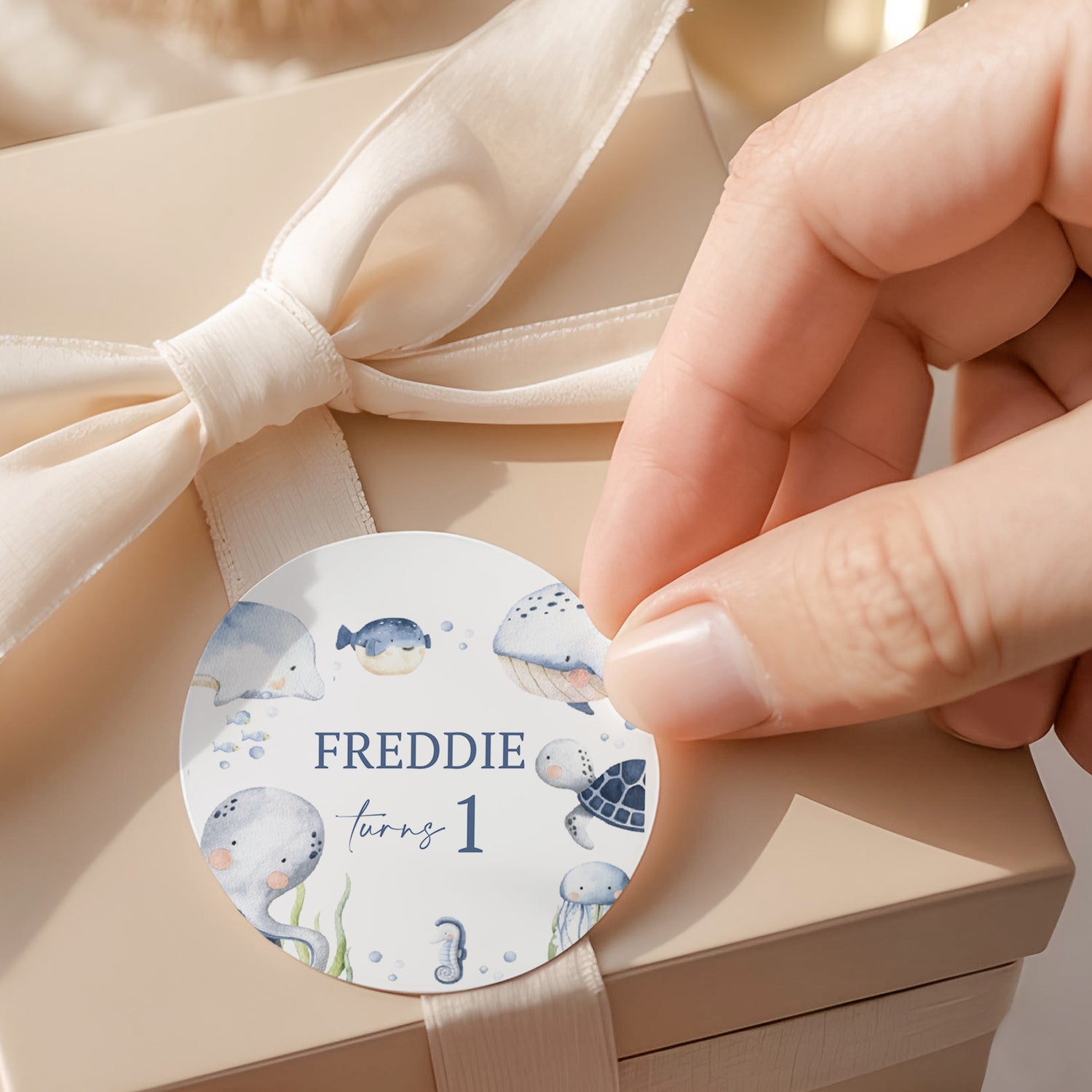 Round sea-themed label with whales, bubbles, and text 'FREDDIE turning 1'
