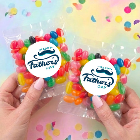 Personalised jelly bean bags with multicolor beans and Happy Father's Day round labels, held in hands.
