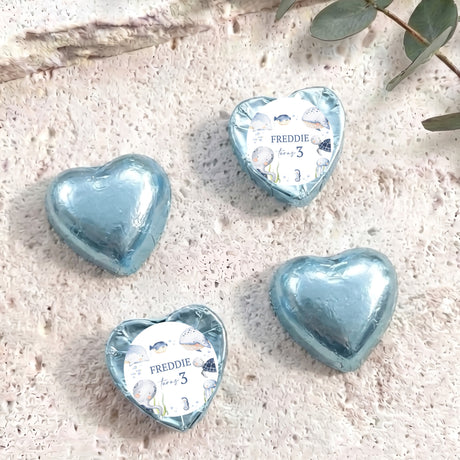 Personalised foil-covered blue chocolate heart with name Freddie on a white label