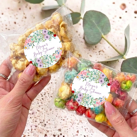 Personalised popcorn bags with floral round labels, filled with mixed popcorn, held in hands