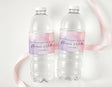 Personalised water bottle labels on clear bottles, pink-purple and gold text