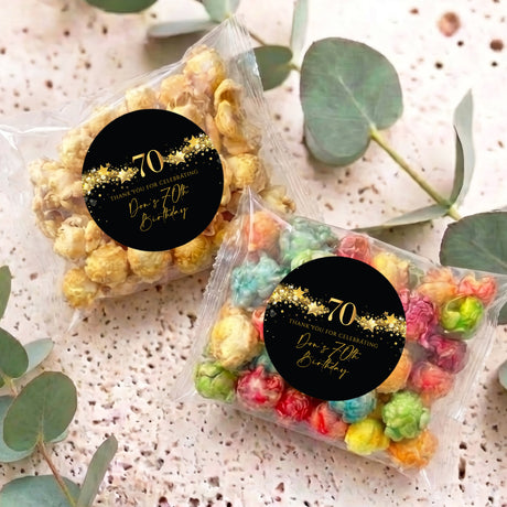 Two 70th birthday popcorn bags with black-and-gold 70 star stickers and multicolor popcorn.