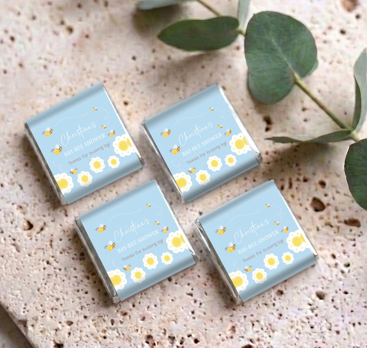 Four blue mini personalized chocolate boxes with bee shower wording and flower accents