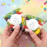 Two personalised lolly bags with clear wrap and round baby shower labels, candies inside