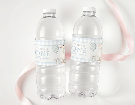 Personalised first birthday labels on two clear plastic water bottles, blue 'ONE' text