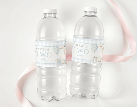 Personalised bottle labels with blue 'Carter is Two' on clear water bottles