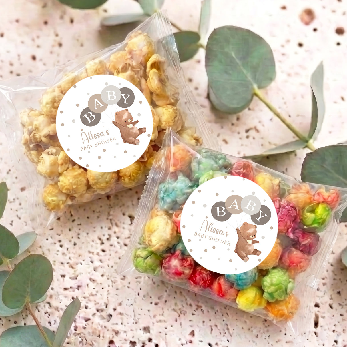 Two personalised baby shower popcorn bags with bear labels and multi-colour popped corn