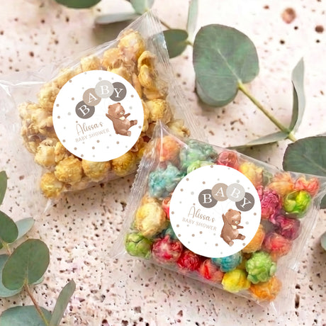 Two personalised baby shower popcorn bags with bear labels and multi-colour popped corn