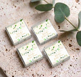 Set of personalized mini chocolate boxes with cream floral design and green leaves