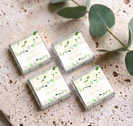 Four cream mini chocolates with floral green leaf wrappers arranged in a group