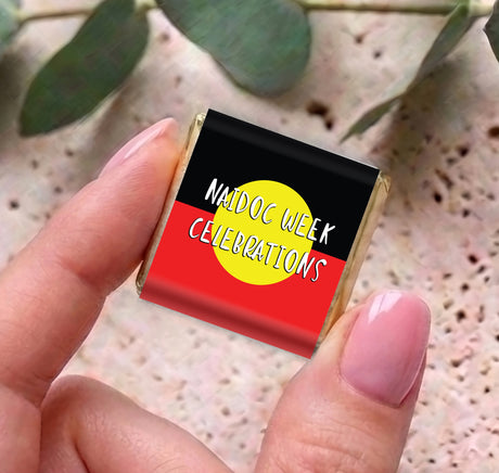 Mini chocolate box with Naidoc Week Celebrations design, held in a hand
